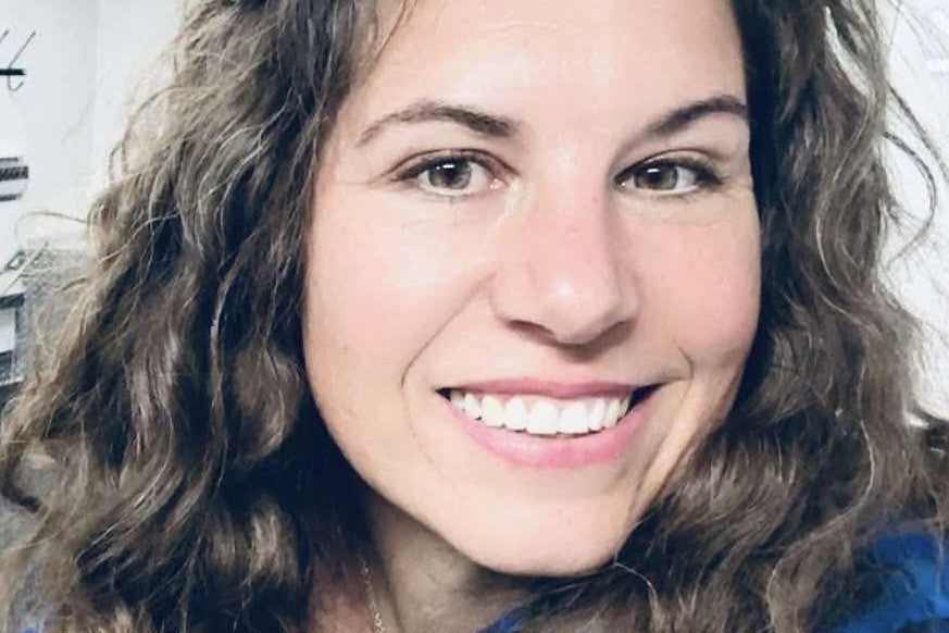 Woman with curly hair wearing a blue jacket indoors